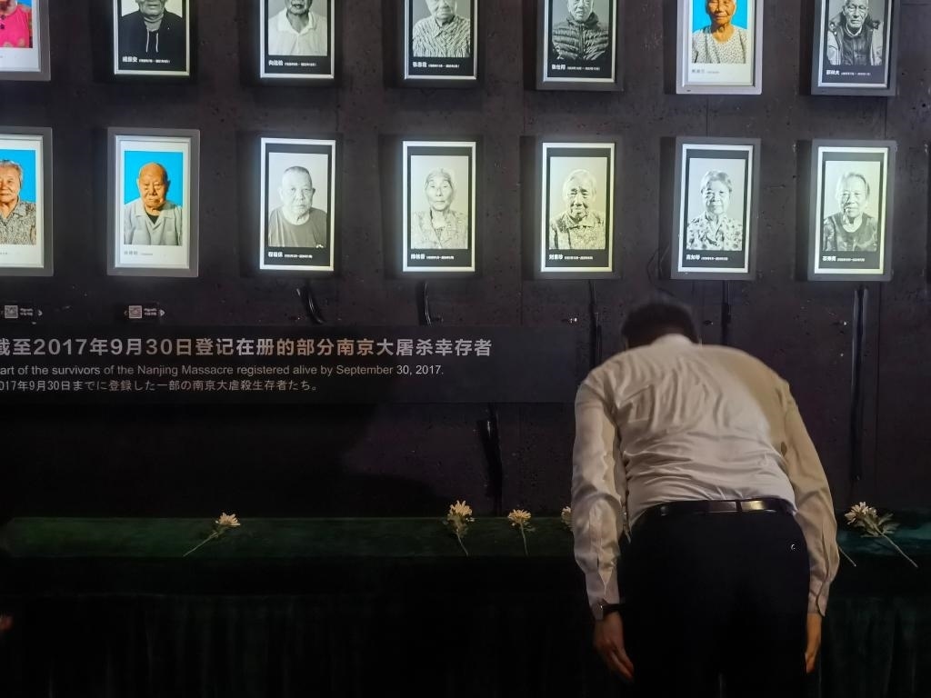 7月18日，人們向離世的南京大屠殺幸存者獻(xiàn)花、鞠躬。新華社記者邱冰清 攝