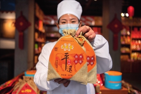 在位于山西省晉中市平遙縣的平遙古城南大街的一家平遙牛肉店內(nèi)，工作人員展示一款牛肉產(chǎn)品（資料照片）楊晨光攝 / 本刊