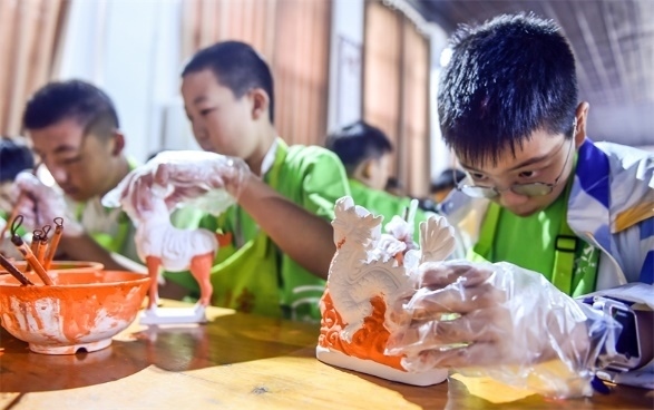 小朋友們?cè)诼尻?yáng)市孟津區(qū)朝陽(yáng)鎮(zhèn)南石山村體驗(yàn)唐三彩素胎施釉技藝。圖片來(lái)源：視覺(jué)中國(guó)