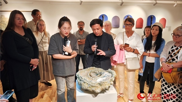 參展人、景德鎮(zhèn)陶瓷大學設(shè)計藝術(shù)學院副院長余劍峰（中）向來賓介紹參展作品。人民網(wǎng)記者 殷淼攝