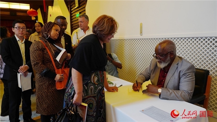 譚哲理在活動現(xiàn)場簽名贈書。人民網(wǎng) 劉暢攝