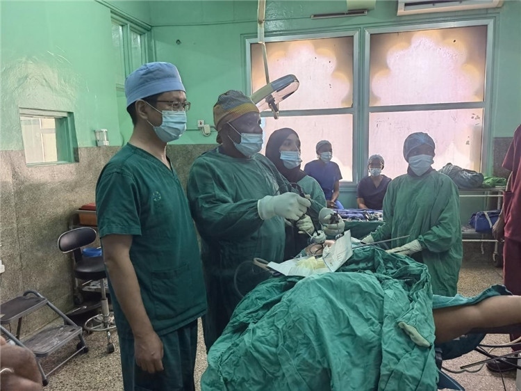 隊長蔣國慶（左一）關注當地醫(yī)生手術情況。中國援桑醫(yī)療隊供圖