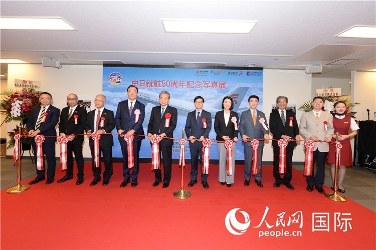 與會(huì)嘉賓共同為中日通航50周年紀(jì)念圖片展開幕剪彩。馮學(xué)敏攝