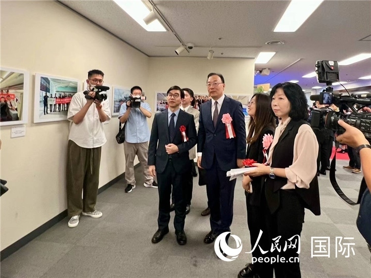 中國(guó)國(guó)際航空日韓地區(qū)支社支社長(zhǎng)馮力為中國(guó)駐日本大使館臨時(shí)代辦施泳等嘉賓介紹展出圖片。人民網(wǎng) 許可攝