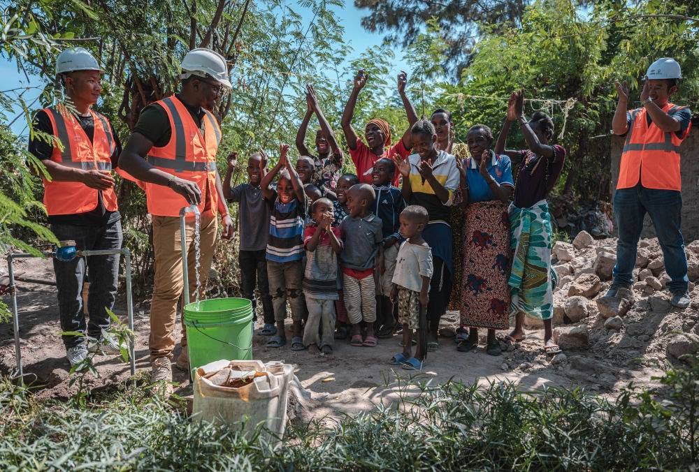 2023年6月13日，在坦桑尼亞姆萬扎省米松圭，工作人員接通水管后贏得當(dāng)?shù)鼐用窆恼茪g呼。新華社記者 王冠森 攝