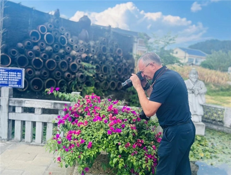 遠(yuǎn)處黔北民居錯落有致，近處一只黑色的蝴蝶穿梭于粉紫色三角梅花叢間隙，與俄羅斯“大歐亞”總編輯弗拉基米爾·別列日內(nèi)赫的鏡頭玩起了捉迷藏，“你追我逃，不亦樂乎”。（張亞欣攝）