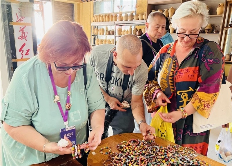 歐亞媒體考察團成員在母氏陶藝館內(nèi)挑花了眼，色彩絢麗、質(zhì)地均勻的陶藝手串讓他們愛不釋手?！斑@里的東西都太實惠了！”塔吉克斯坦《索格特真理報》政論部主任娜塔利婭·多羅費耶娃說?；宓奶厣a(chǎn)品物美價廉，讓考察團成員為家人好友買到了心儀的禮物，也為此次以四川成都為起點，路經(jīng)南充、廣安至貴州遵義的考察行程畫上了圓滿句號。（張亞欣攝）