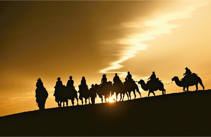 新時代以來，文化和旅游深度融合發(fā)展體制機(jī)制不斷健全，成功走出了一條獨具特色的中國旅游發(fā)展之路。圖為2024年9月1日清晨，游客在甘肅省敦煌市鳴沙山月牙泉景區(qū)乘騎駱駝，欣賞大漠風(fēng)光，體驗絲路風(fēng)情。 新華社發(fā) 張曉亮/攝