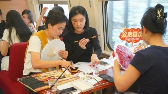 10月1日，旅客們在G1634次列車上給油紙傘作畫。新華社記者周義 攝