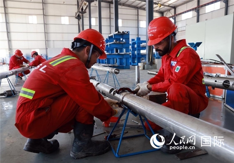 中伊員工共同在檢修鉆井設(shè)備。人民網(wǎng)記者管克江攝