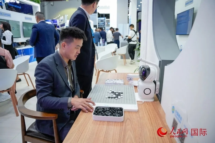 觀眾在中國移動國際有限公司展臺體驗智慧圍棋機器人。人民網 塔里克·易卜拉欣攝