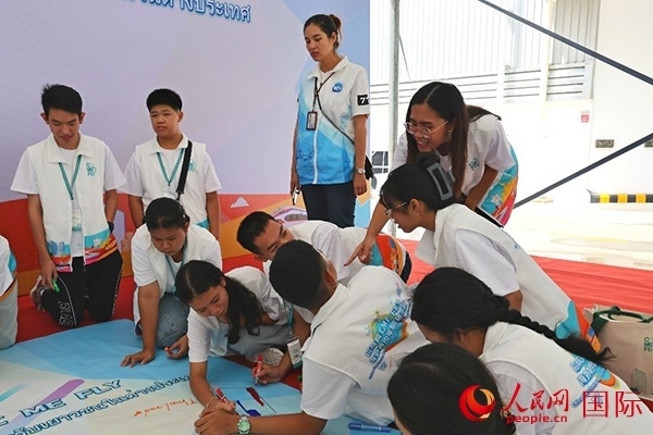 泰國(guó)學(xué)生在開(kāi)營(yíng)儀式展板上繪制圖案。人民網(wǎng)記者 白元琪攝