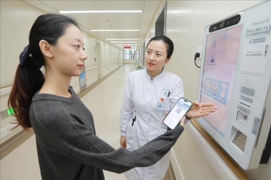 醫(yī)護(hù)人員引導(dǎo)患者在自助機(jī)前辦理自助入院手續(xù)。圖片來源：山東第一醫(yī)科大學(xué)第二附屬醫(yī)院