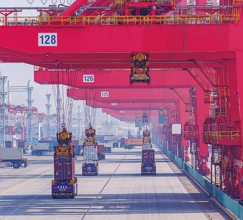 共建“一帶一路”國家在工作制度對接、技術標準協(xié)調、檢驗結果互認等方面強化合作、統(tǒng)一標準，貿(mào)易自由化便利化水平不斷提升。上海洋山港海關對接共建國家進出口貨物相關標準，推動通關一體化方式申報，提升通關效率。圖為無人駕駛的全自動導引車在洋山港穿梭往來，搬運集裝箱。王初 攝