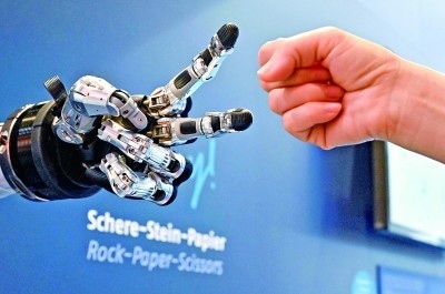 在德國漢諾威工博會上，參觀者與一款智能機器人進行“石頭剪子布”游戲。新華社發(fā)