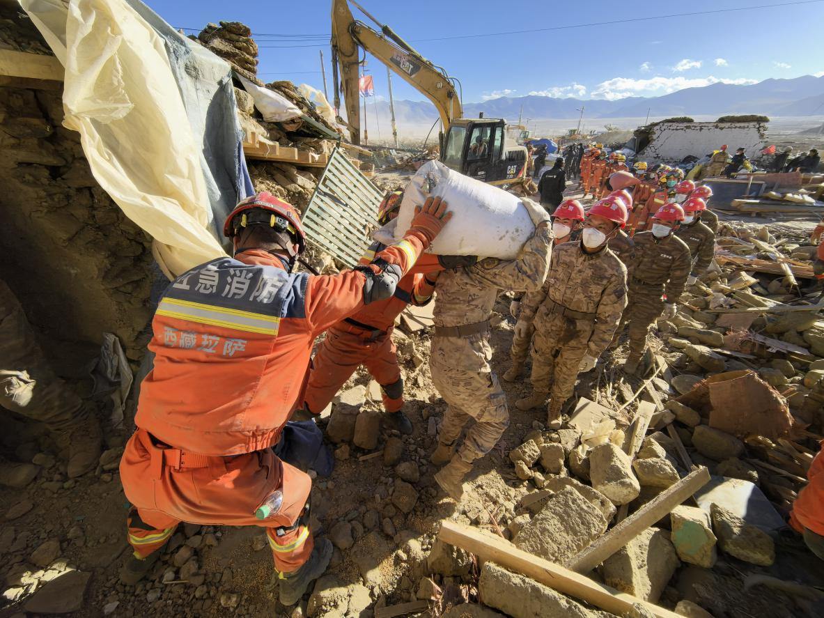 1月11日，定日縣長(zhǎng)所鄉(xiāng)古榮村，應(yīng)急消防等救援人員排隊(duì)接力搶運(yùn)掩埋在倒塌房屋下的群眾財(cái)物。人民日?qǐng)?bào)記者楊翹楚攝