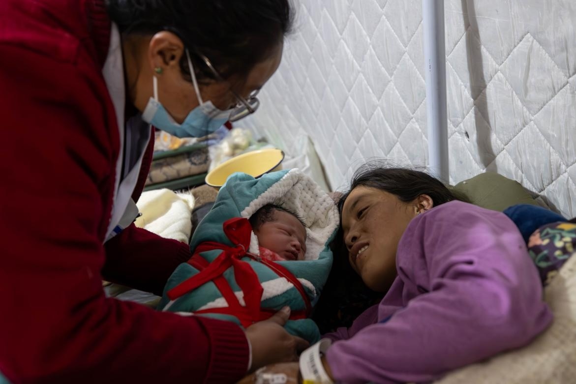 1月10日，定日縣中心醫(yī)院的婦產(chǎn)科醫(yī)生悉心照看一位母親和她懷里的新生兒。人民日?qǐng)?bào)記者張武軍攝