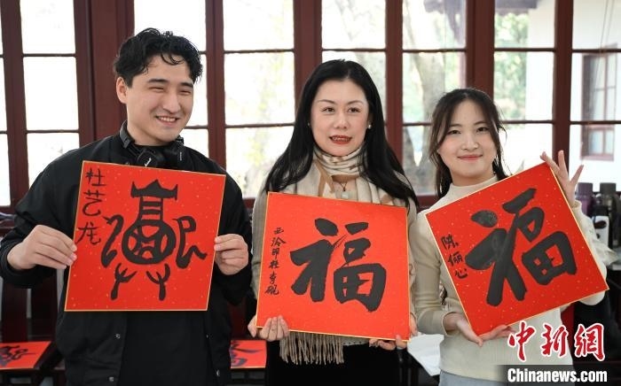 1月20日，外籍留學(xué)生和西泠印社社員李硯(中)展示各自創(chuàng)作的福貼。當(dāng)日，來自巴西、馬來西亞、加納、哈薩克斯坦的外籍留學(xué)生在浙江杭州西泠印社體驗(yàn)福貼、春聯(lián)和篆刻，感受古老的中國傳統(tǒng)文化。中新社記者 王剛 攝