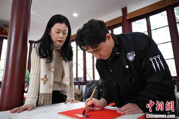 1月20日，外籍留學(xué)生在西泠印社社員李硯指導(dǎo)下寫福。當(dāng)日，來自巴西、馬來西亞、加納、哈薩克斯坦的外籍留學(xué)生在浙江杭州西泠印社體驗(yàn)福貼、春聯(lián)和篆刻，感受古老的中國傳統(tǒng)文化。中新社記者 王剛 攝
