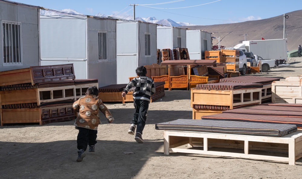 2025年1月13日，在定日縣嘎旦村，兩個(gè)孩子在剛運(yùn)來(lái)的兩排藏床間奔跑。新華社記者丁增尼達(dá) 攝