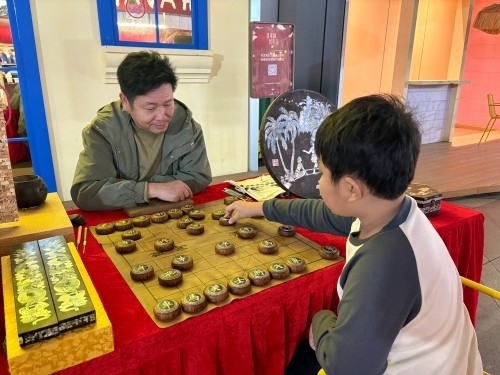 柯秋楓與市民下椰雕象棋。人民網(wǎng) 陳葉欣攝