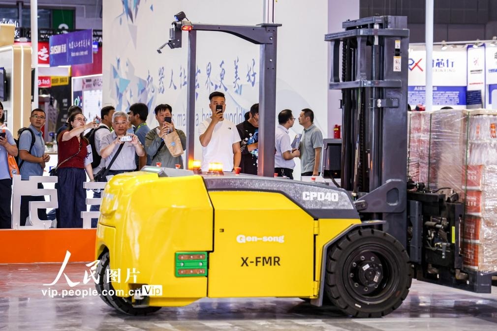 第24屆中國工博會現(xiàn)場，觀眾觀看叉取機(jī)器人作業(yè)演示。王初攝（人民圖片網(wǎng)）