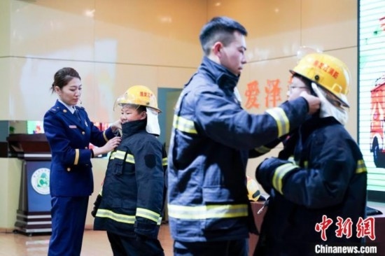 圖為學生們現(xiàn)場穿戴消防頭盔和戰(zhàn)斗服。中新社記者 趙宇航 攝