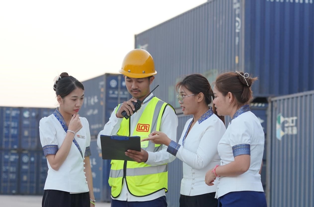 萬象南站貨運值班員陳尼啦（左一）與同事在一起討論工作。老中鐵路有限公司供圖