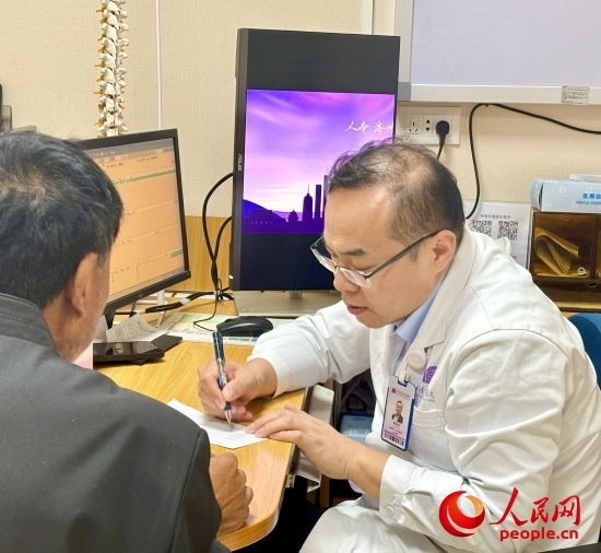 路桂軍接診時(shí)為患者寫下用藥提示。人民網(wǎng)記者 金慧慧攝