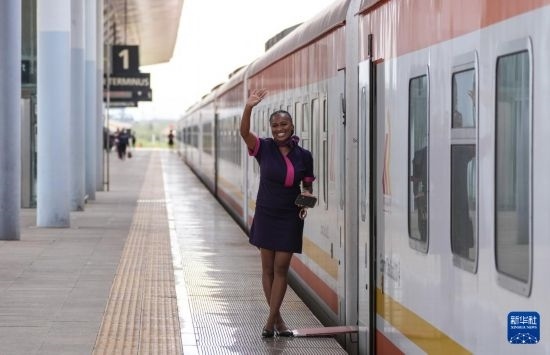 5月31日，在蒙內(nèi)鐵路內(nèi)羅畢站，一名乘務(wù)員在即將開往蒙巴薩的E2次列車旁等候乘客。新華社記者 李亞輝 攝