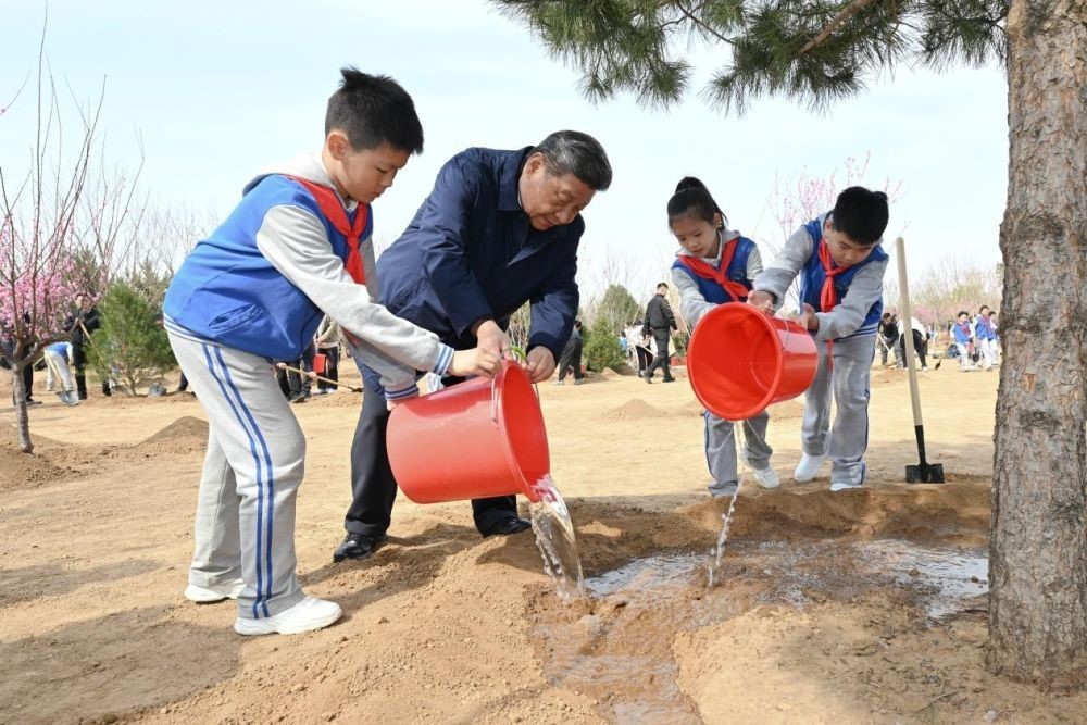 2025年4月3日，習(xí)近平總書記等來到北京市豐臺區(qū)永定河畔參加首都義務(wù)植樹活動。這是習(xí)近平總書記同少先隊員一起給剛栽下的樹苗澆水。新華社記者 謝環(huán)馳 攝